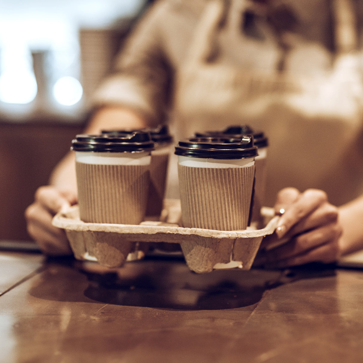 staff handing over 4 cups of coffee in cup holder