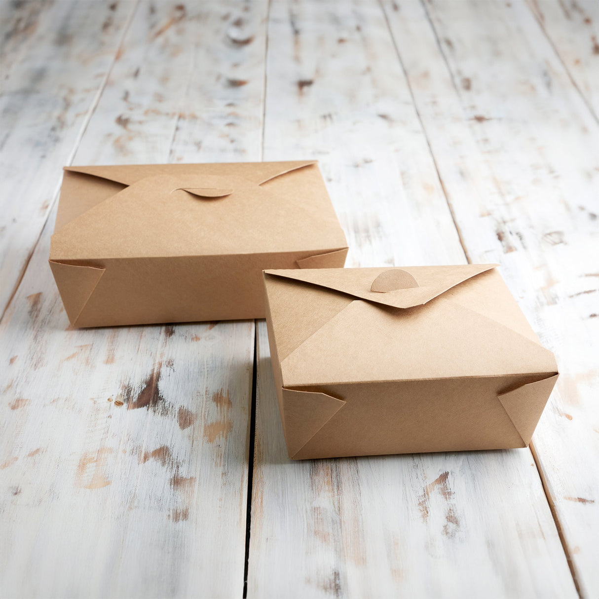 2 closed kraft boxes on light coloured wood planks