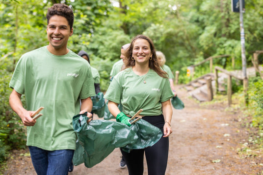 happy people picking up garage with tongs and garbage bag, protecting environment