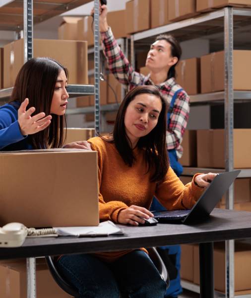 3 Asian employees looking at laptop and discussing issues