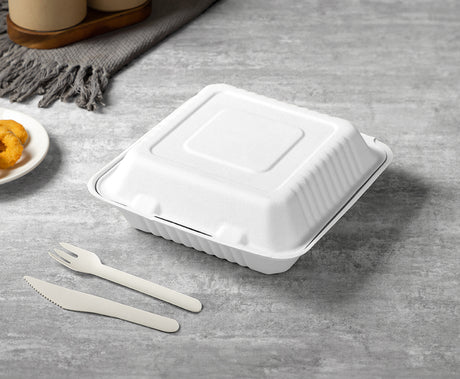 white compostable clamshell food container with paper fork and paper knife.