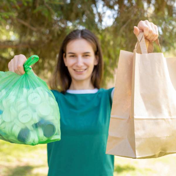 a smiling young girl holding 2 bags of waste